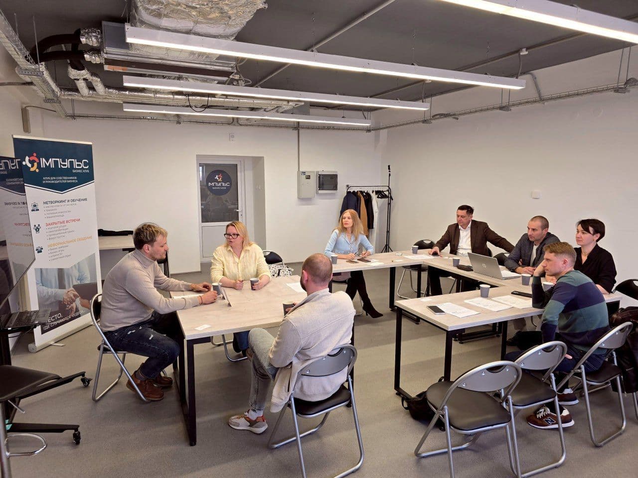 Group of professionals gathered around a U-shaped conference table during a meeting.